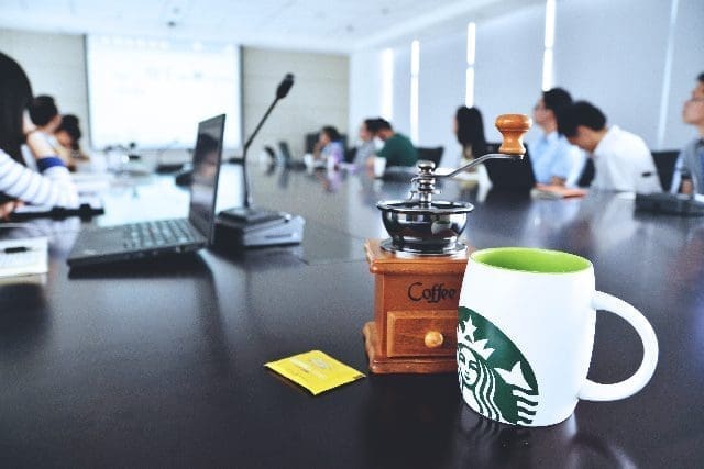 MKYF A Starbucks coffee mug sits on a table in a Kappa League Conference room.